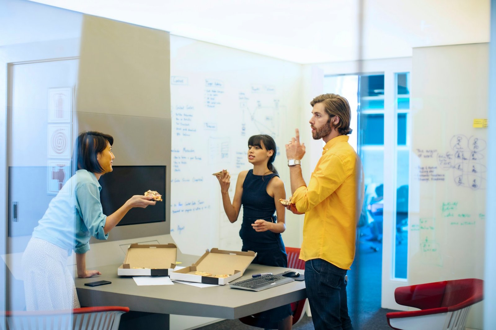 Business people in futuristic office having a meeting, eating pizza